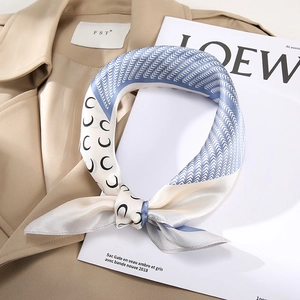 Silk square scarf featuring blue moon prints and herringbone patterns on khaki trench coat