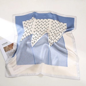 Detailed view of silk square scarf featuring crescent prints and blue geometric patterns