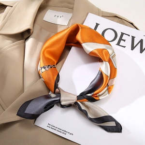 Detail of silk square scarf with geometric patterns tied on a trench coat lapel