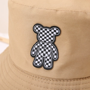 Détail de l'écusson brodé d'ours et texture en coton de ce chapeau bob de couleur kaki