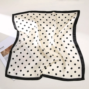 Close-up of elegant silk neck scarf with black polka dots on ivory and black border