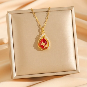 Golden teardrop necklace featuring red gemstone and zircon accents on premium satin