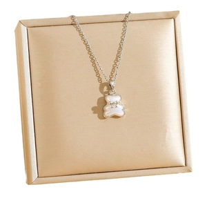 Collana con pendente a forma di orso con inserto iridescente e fiocco su scatola di seta
