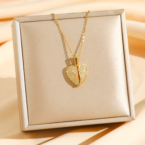 Elegante collar con colgante de corazón dorado con alas de cristal sobre joyero
