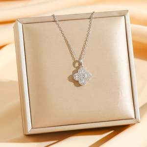 Collier trèfle à quatre feuilles en argent avec zircons posé sur un coffret à bijoux de luxe