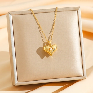 Titanium heart pendant necklace with sunburst texture and pearl on gold display