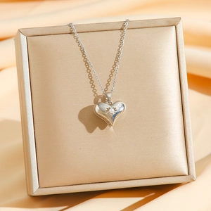 Elegant silver heart necklace with pearl inlay displayed on silk for a luxury gift look