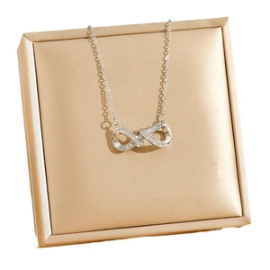 Collier symbole infini avec pavé de cristaux sur un coffret à bijoux doré élégant