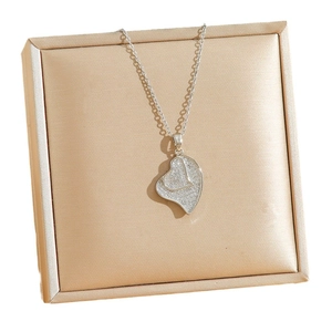 Silver-colored heart necklace with micro-pave crystals on a champagne jewelry box