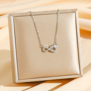 Silver infinity necklace with heart-shaped stone on elegant jewelry box display