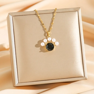 Collier vintage doré avec pierre noire et perles blanches sur satin couleur champagne