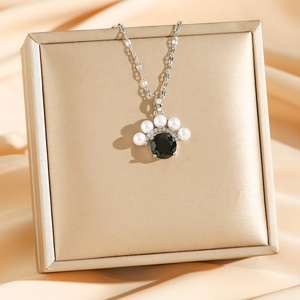 Collier vintage avec pendentif en pierre noire et perles blanches sur fond de satin chic