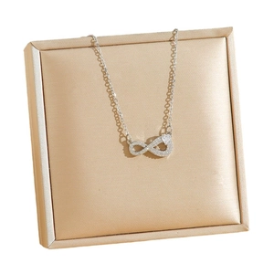 Minimalist stainless steel infinity necklace with heart stone on gold satin cushion