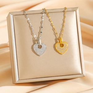 Sparkling pave heart necklaces in gold and silver finish on luxury silk background