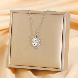 Collier trèfle argenté avec cristaux de zircon blancs posé sur une boîte à bijoux