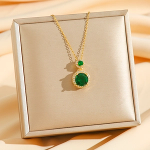 Vintage gold emerald pendant necklace with white zircon halo on champagne silk stand
