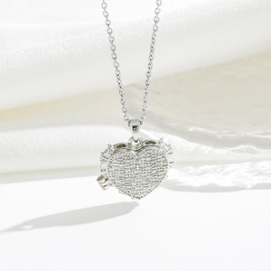 Gros plan du collier médaillon cœur en argent avec zircons sur un tissu en soie