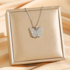Silver butterfly pendant necklace with sparkling stones on champagne satin background