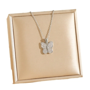 Collier avec pendentif papillon et zircons brillants sur un coffret à bijoux champagne