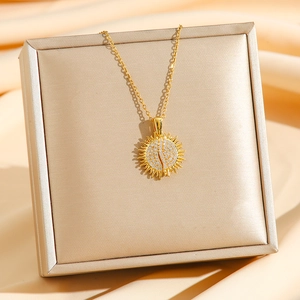 Elegant gold sunburst pendant necklace with white zircon pavé on a silk fabric background