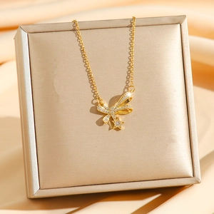 Collana con fiocco di camelia dorata e stelle di zirconi su sfondo di raso di lusso