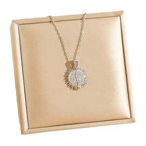 Sparkling silver sunburst pendant necklace with white zircons in a golden jewelry box