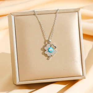 Detailed macro of silver four-leaf clover pendant with blue evil eye and zircons