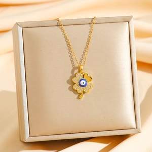 Golden clover pendant necklace with diamond accents and blue evil eye bead on satin