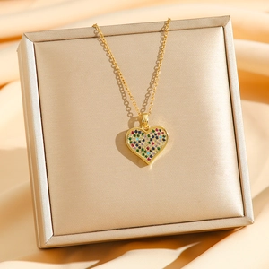 Collana a cuore dorata con ciondolo in zircone colorato su sfondo in raso di lusso