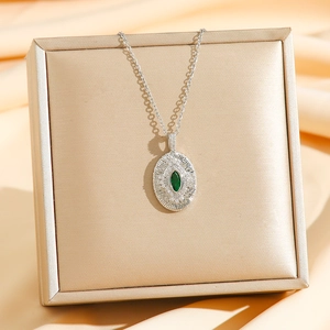 Vue macro du collier émeraude avec gravures radiales sur un support en soie douce