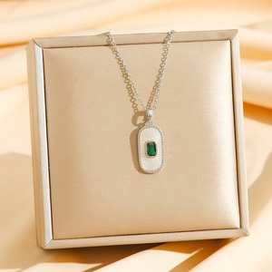 Detail of square 18K gold stainless steel pendant with white shell and green zircon