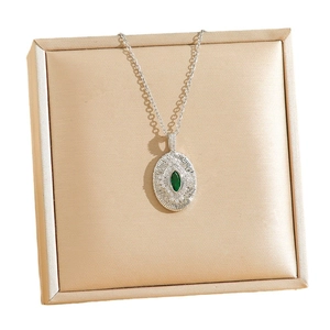 Collier de luxe avec pendentif émeraude et zircon sur boîte à bijoux en satin champagne