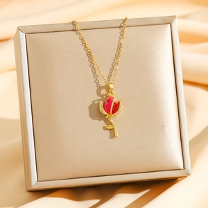 Détail d'un collier tulipe dorée avec émail rouge et zircons sur tissu satiné