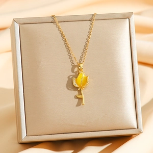 Détail du collier tulipe dorée avec émail jaune et zircon sur un tissu en soie