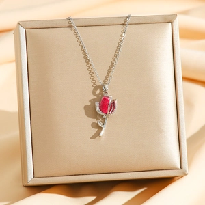 Gros plan du pendentif tulipe rouge avec zircons sur un tissu de soie luxueux