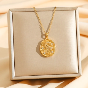 Close-up of golden oval pendant with seahorse relief and sparkling zircon inlay