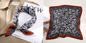 Detail of silk scarf with navy paisley pattern and rust-red border on trench coat