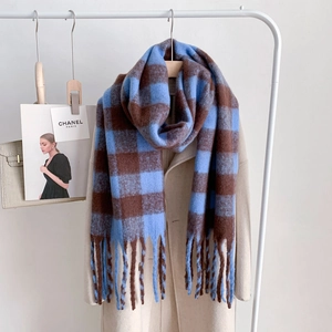 Blue and brown checkered oversized mohair scarf with fringe hung on a beige coat