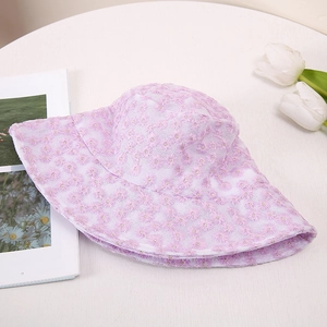 Détail d'un chapeau de soleil en dentelle lilas avec broderie florale de marguerites