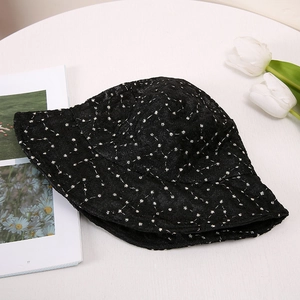 Détail de la texture d'un chapeau bob en dentelle noire avec broderie de marguerites