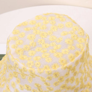 Gros plan de la broderie de marguerites jaunes sur un chapeau bob en dentelle blanche