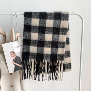 Detailed view of checkered mohair scarf with thick tassels hanging on a rack
