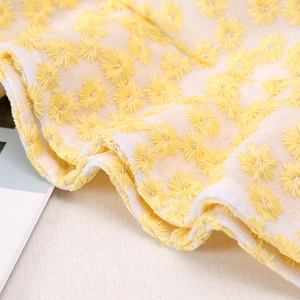 Détail de broderies marguerites jaunes sur chapeau en dentelle crème respirant
