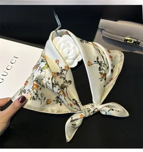 Close-up of floral silk scarf on black sweater with cream base and orange flower pattern