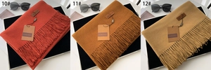Detailed macro view of solid color tassel scarves in brick red, caramel, and camel tones