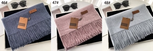 Close-up of fringe scarves in grey blue, lotus pink and light grey with brand tags