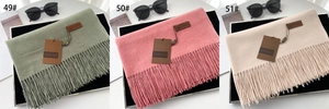 Detailed close-up of thick tassels and soft cashmere-like texture in three pastel colors
