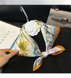 Detailed close-up of 100% silk scarf with orange trim and elegant floral camellia pin