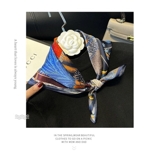Detailed view of 100% mulberry silk scarf with vibrant feather patterns on a black sweater