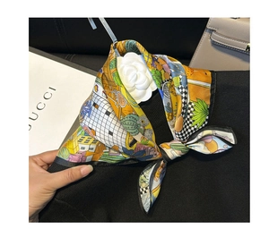 Close-up of bright yellow silk scarf with cactus print tied on a black knit collar